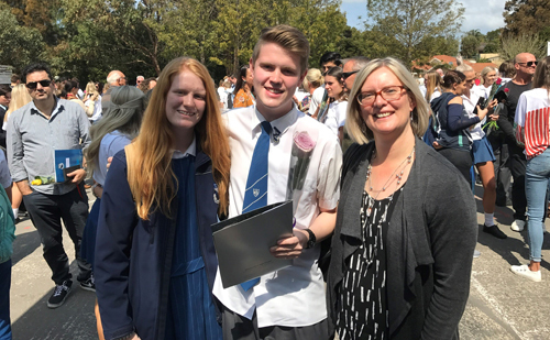 William Marshall with two female family members face camera smiling; they are outdoors with a crowd of mingling people. William is holding a dark-couloured folio. William Marshall with two female family members face camera smiling; they are outdoors with a crowd of mingling people. William is holding a dark-coloured folio.