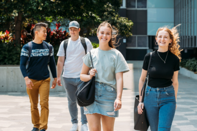Four young students on campus walking towards camera