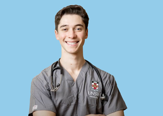 profile image of medicine student Josh Lowinger wearing medicine scrubs with UNSW logo standing in front of a light blue background