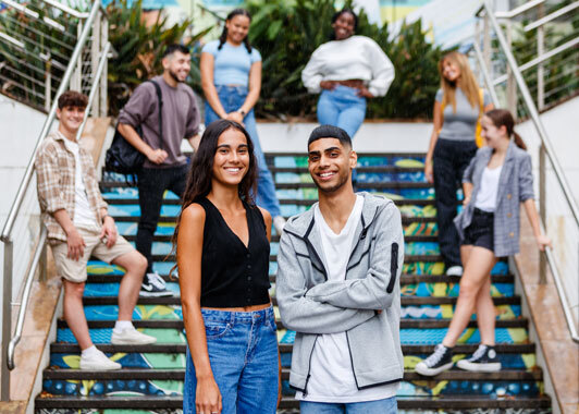 Group of students standing on a staircase outside with two students standing together in the foreground