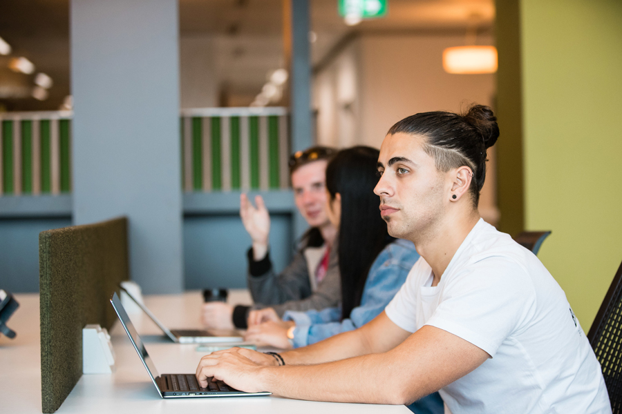 Three students sit side by side – two are chatting, two are sitting in front of a laptop Three students sit side by side – two are chatting, two are sitting in front of a laptop