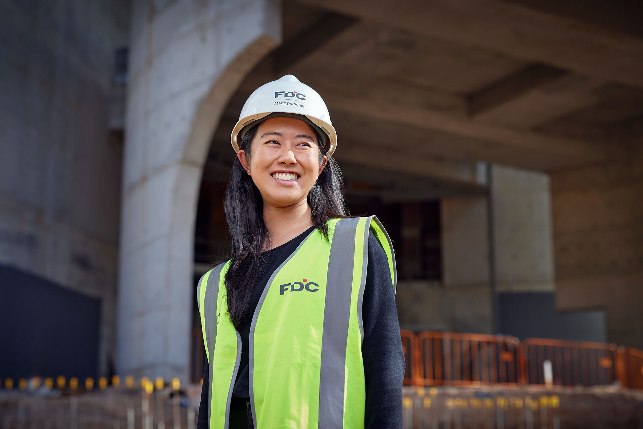 profile image of sophie ung on a constructions site, wearing a white hard hat and yellow high viz vest