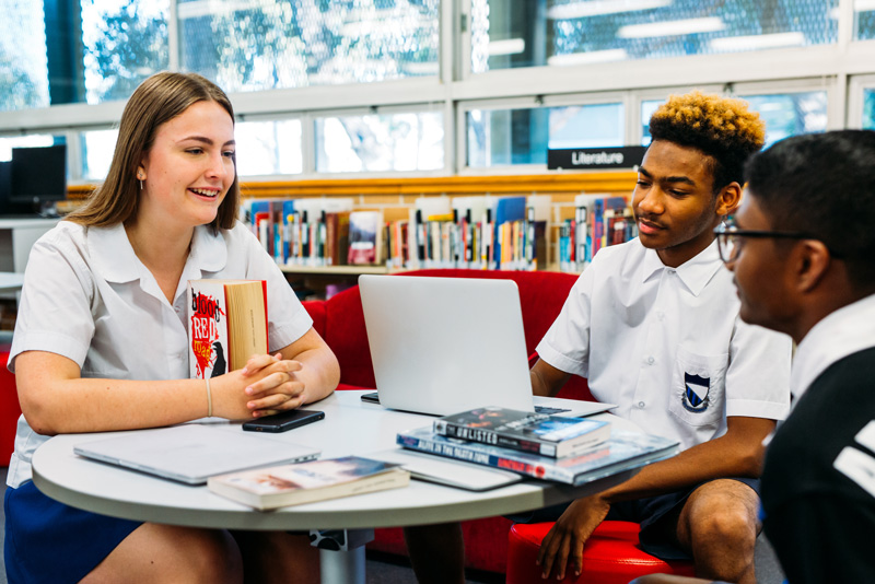 Three senior school students sitting together with laptop and books. Three senior school students sitting together with laptop and books.